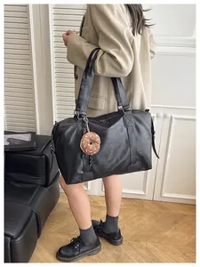 Detailed view of black large leather tote bag with a cute plush donut keychain charm