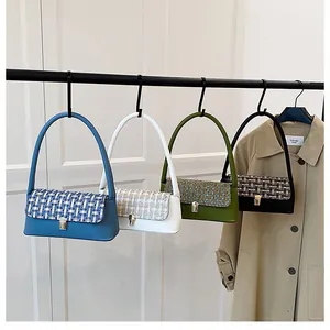 Detail showing assorted tweed and leather baguette bags hanging on a black metal rack