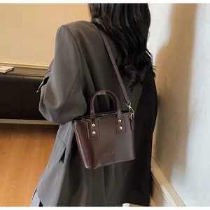 Dettaglio borsa a tracolla marrone lucido con borchie dorate e goffratura moda