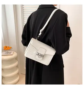 Detail showing white leather shoulder bag with geometric embossing on a black suit blazer