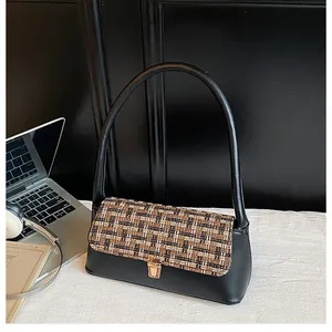 Close-up of the vintage tweed pattern fabric and golden square clasp on a black shoulder bag