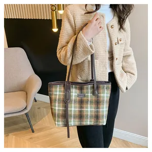 Detail of vintage green plaid wool tote bag with brown leather handles and fashion logo
