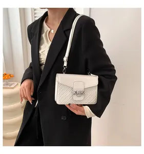 Detailed view of white embossed crossbody bag with silver buckle and quilted texture