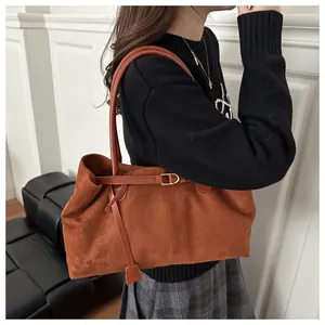 Close-up of matte vintage brown tote bag with leather strap and golden metal buckle