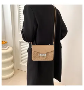 Detail of tan crossbody bag with woven texture and silver hardware on a female model