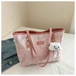 Detail of pink tote bag with wavy embroidery and a cute cloud plush charm accessory