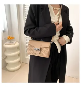 Detail of a chic beige crossbody bag with woven texture and silver hardware on a model