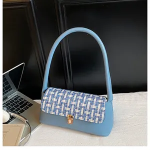 Detail of light blue handbag with woven tweed flap and golden metallic square lock
