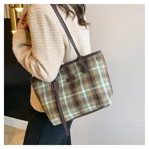 Close-up of vintage plaid wool tote bag featuring a brown leather strap and fashion label