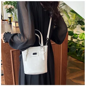 Detailed side view of white bucket bag with black rectangular patch and adjustable straps