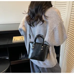 Dettaglio di borsa tote in pelle nera lucida con testo a rilievo e cuciture fini