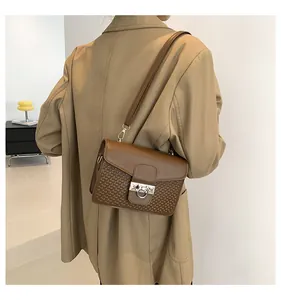 Close-up of vintage brown crossbody bag featuring embossed texture and metal ring buckle