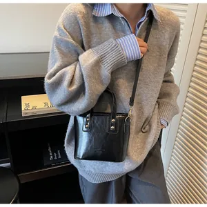 Dettaglio di una borsa a tracolla nera lucida con rivetti metallici e logo HEI&MISS