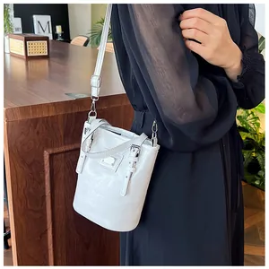 Detail view of white bucket bag with silver metal decor and adjustable shoulder strap