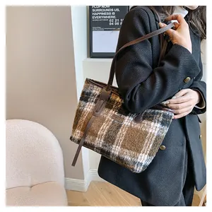 Detail of vintage plaid tweed tote bag with leather strap worn as an underarm shoulder bag