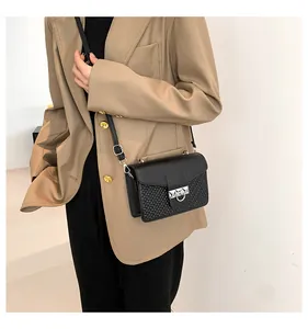 Detail of black leather crossbody bag featuring textured weave and silver metal buckle