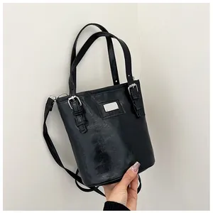 Close-up of black oil wax leather bucket bag with silver metal plaque and buckle details
