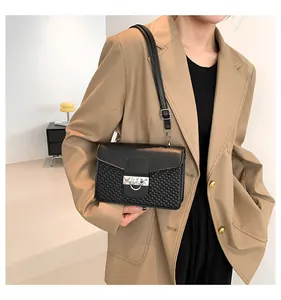 Close-up of black woven leather handbag with silver buckle worn by a model
