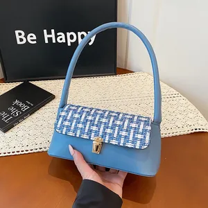 Sky blue women's underarm bag with tweed flap design and gold lock buckle in hand
