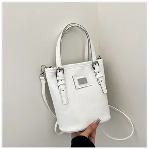 Detailed close-up of white leather bucket bag featuring silver buckles and strap