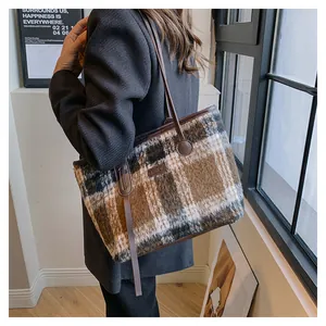 Detailed close-up of a large plaid wool tote bag with leather straps and fashion label