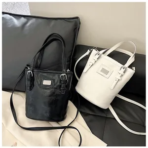 Detailed view of black and white bucket bags featuring oil-wax leather and metallic accents