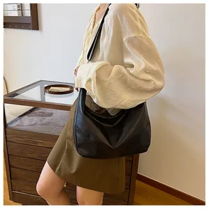Detail of a large black hobo bag with a soft lychee texture and adjustable strap