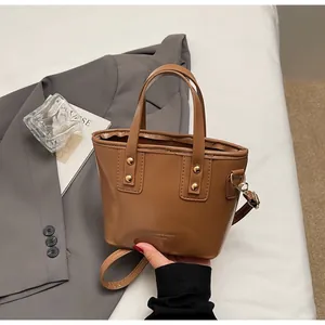 Dettaglio mini borsa tote in pelle marrone con rivetti dorati e tracolla staccabile