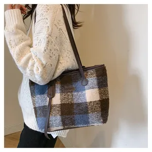 Detail of blue and coffee plaid woolen tote bag featuring a leather Fashion patch