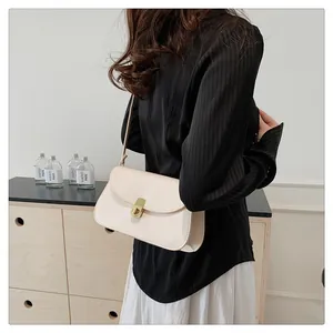 Détail du sac de selle en cuir crème minimaliste avec une boucle métallique dorée