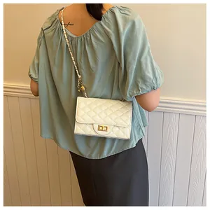 Detailed close-up of white quilted crossbody bag with gold chain strap and metal lock