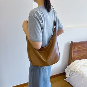 Brown large capacity leather hobo shoulder bag with adjustable strap worn by model