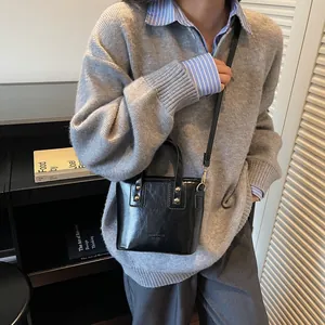 Elegante borsa a secchiello in pelle PU lucida nera con manici e tracolla vista sul modello