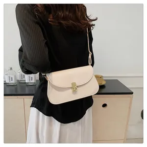 Détail de la sacoche en cuir crème avec son fermoir rotatif rectangulaire doré élégant