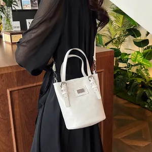 White oil wax leather bucket bag with silver buckles and adjustable strap on a woman