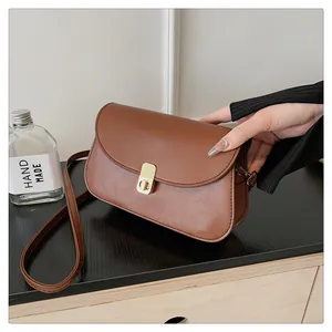 Vue détaillée du sac besace marron vintage avec fermoir doré sur bois sombre