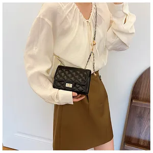 Close-up of a black quilted crossbody bag with gold metal lock and leather chain strap