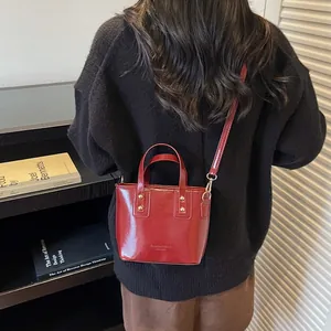 Alla moda borsa a secchiello bordeaux lucida con rivetti dorati e manico da donna