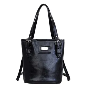 Glossy black leather bucket bag with metallic details and minimalist handle design