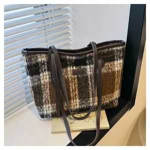 Close-up of vintage plaid wool tote bag with leather straps and Fashion label on a window sill