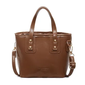 Borsa a secchiello marrone in similpelle lucida con borchie dorate e tracolla moda