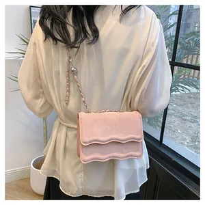 Detailed shot of pink crossbody bag featuring wavy edge flap and metal chain strap