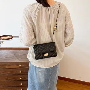 Quilted black chain crossbody bag with gold ball accent shown on a model's shoulder