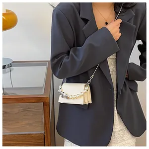 Détail d'un mini sac en cuir blanc crème avec chaîne en perles et détails de cœurs