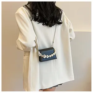 Détail du mini sac bandoulière noir avec sangle décorative en cœurs et perles
