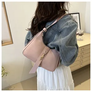 Pink faux leather hobo shoulder bag styled on a model in a cozy interior setting