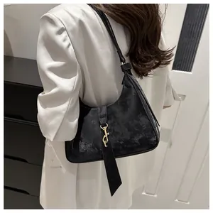 Detail of black textured leather hobo bag with gold hardware and stylish long strap