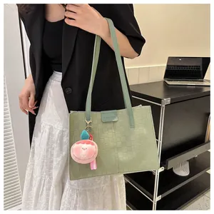 Detail of light green woven tote bag with FASHION label and peach plush pendant charm