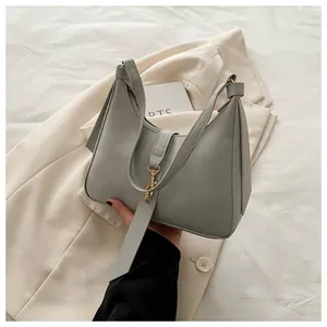 Detail of light gray hobo bag with matte leather finish and gold metal buckle accents