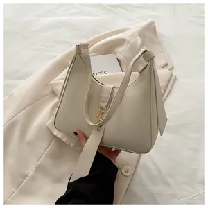 Detail of minimalist beige hobo bag featuring gold hardware and smooth leather finish